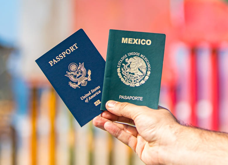 Hand holding U.S. and Mexican passports at border crossing