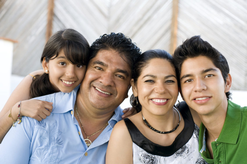 Smiling family of parents with their two children representing parentage declaration