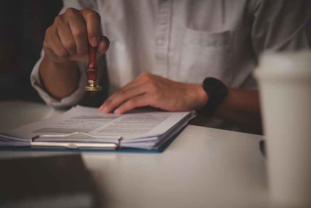 Hand using a seal to notarize a death certificate document